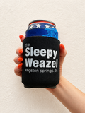 Hand holding a black neoprene koozie with embroidered Sleepy Weazel Kingston Springs TN logo